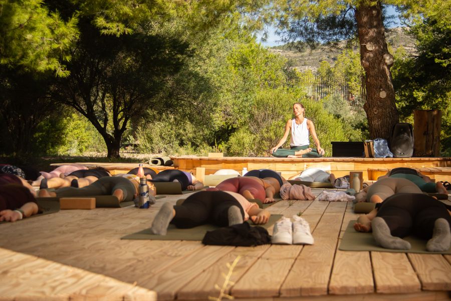 Sesión de meditación colectiva sobre la tarima de madera de Bosque, entre pinos.